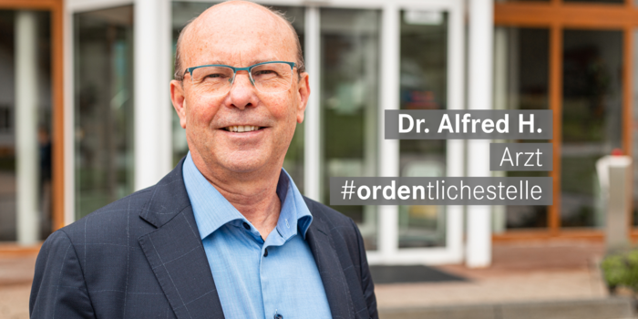  Arzt mit Brille lacht freundlich in die Kamera